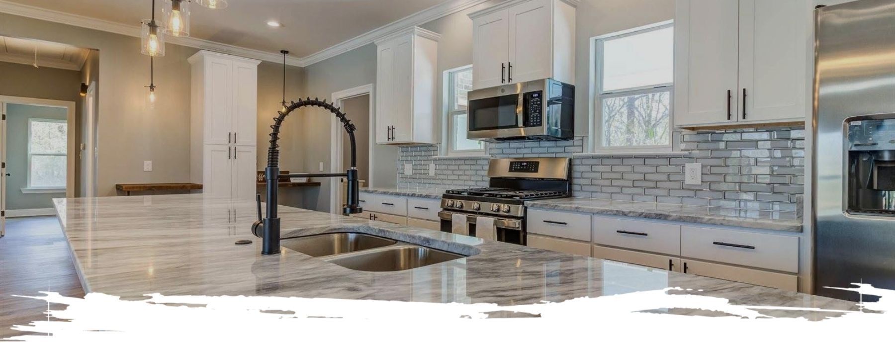 Modern kitchen with white cabinets, stainless steel appliances, and a large island.