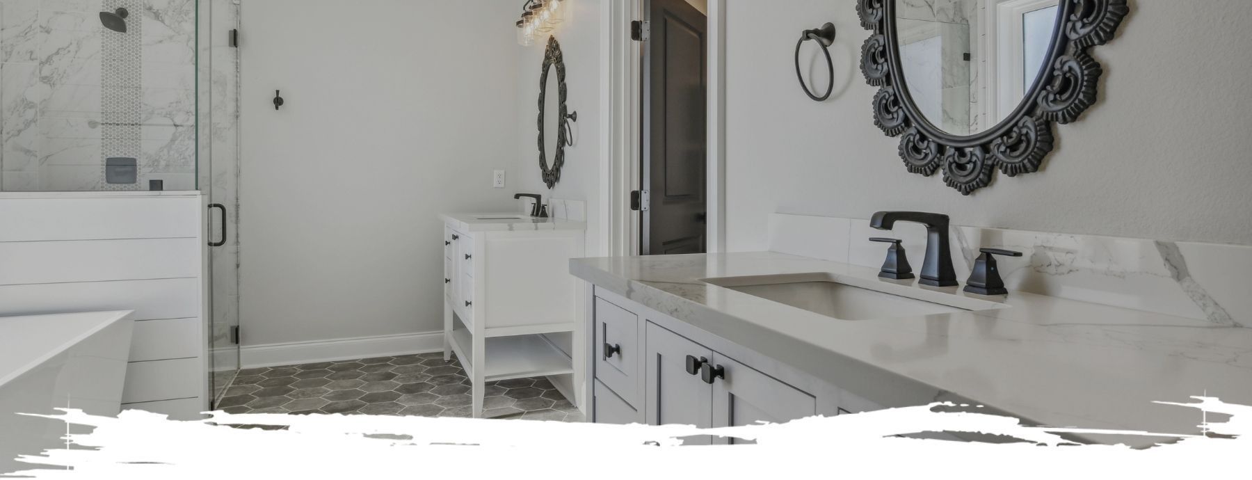 Bathroom with white walls, cabinets, and marble-look countertop. Features black faucets, decorative mirror, and shower.