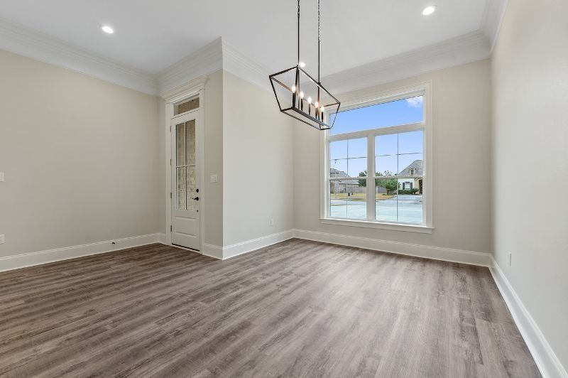 Empty room with hardwood floors, a large window, and a chandelier.