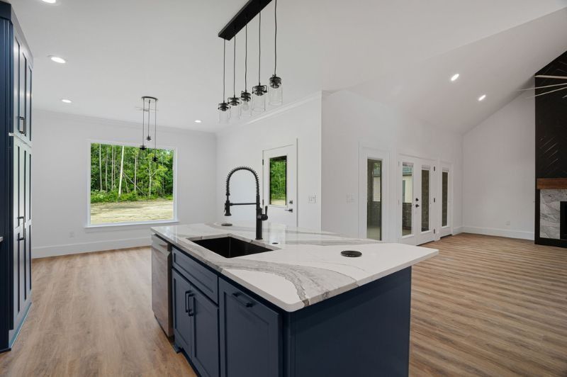 Modern kitchen with blue island, white countertops, and open door to the backyard.