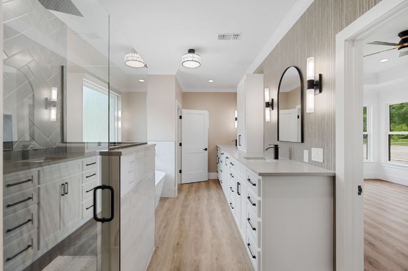 Bathroom with white cabinets, wood-look floors, large shower, and double sinks.