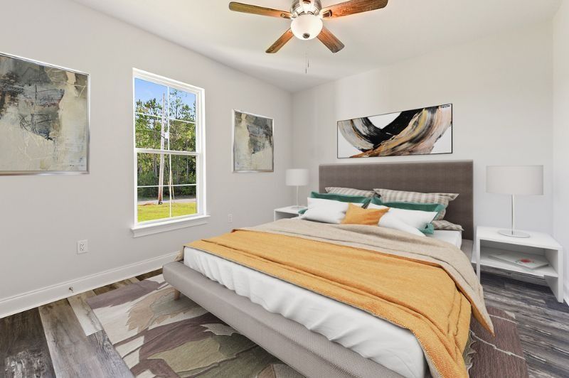 Bedroom with bed, art, and window overlooking greenery.