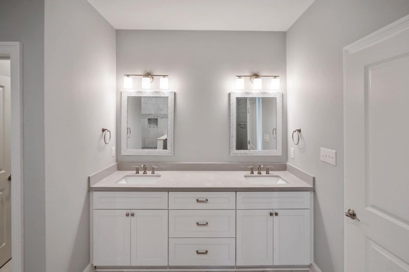 Bathroom with two mirrors above a white vanity with light fixtures and gray countertop.