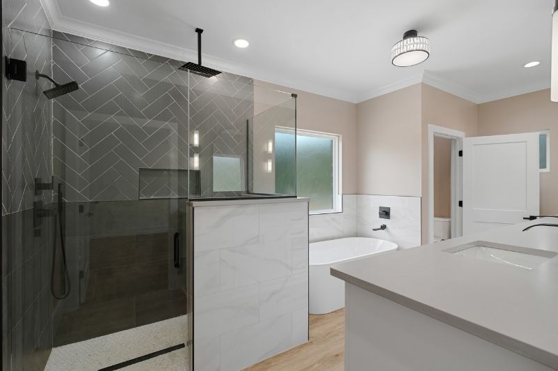 Modern bathroom with glass shower, white countertop, and a round tub.