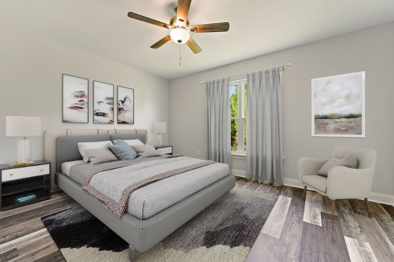 Bedroom with gray upholstered bed, abstract art, armchair, and window with curtains.
