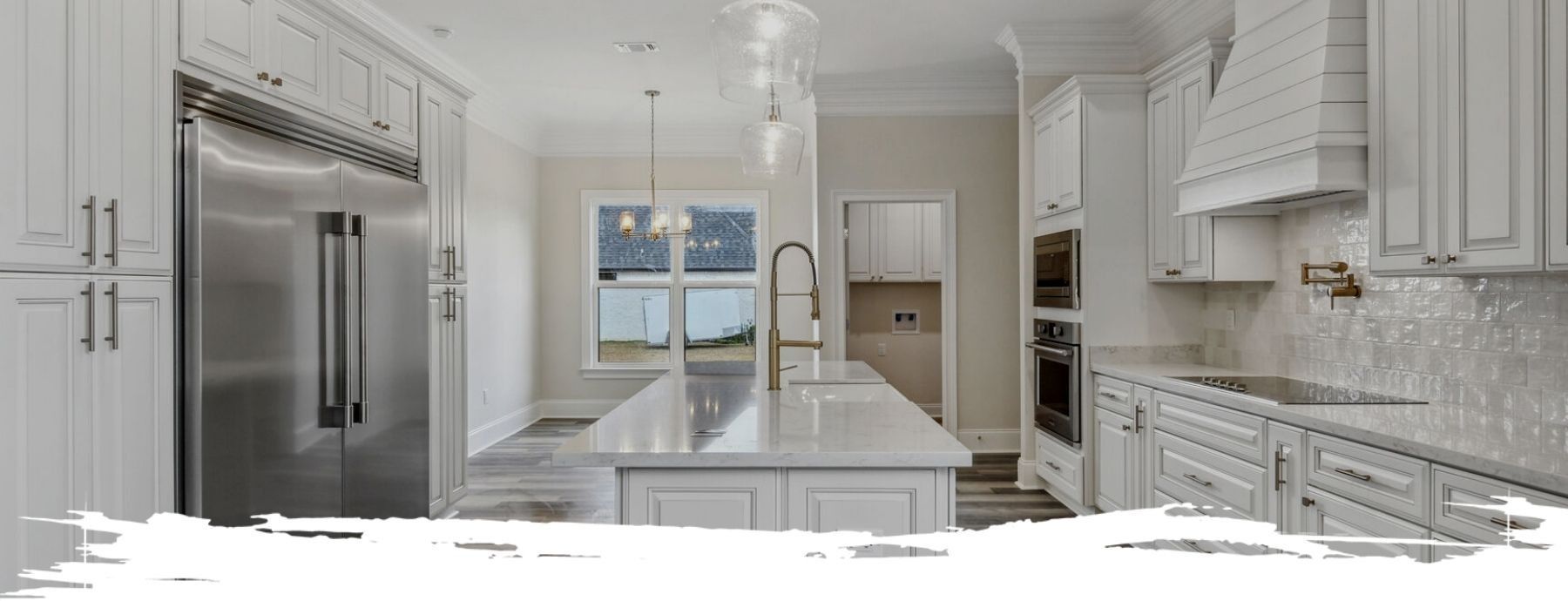 Bright white kitchen with a large stainless steel refrigerator, island, and cabinetry.