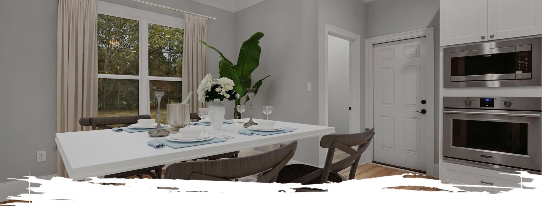 Dining room with a white table set for a meal. Includes chairs, a window, and a built-in oven.