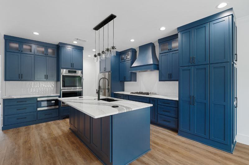 Blue kitchen with white countertops, a central island, and wooden floor.