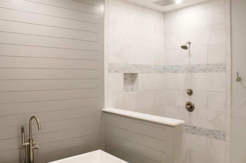 Modern bathroom with a white tiled shower and shiplap wall.