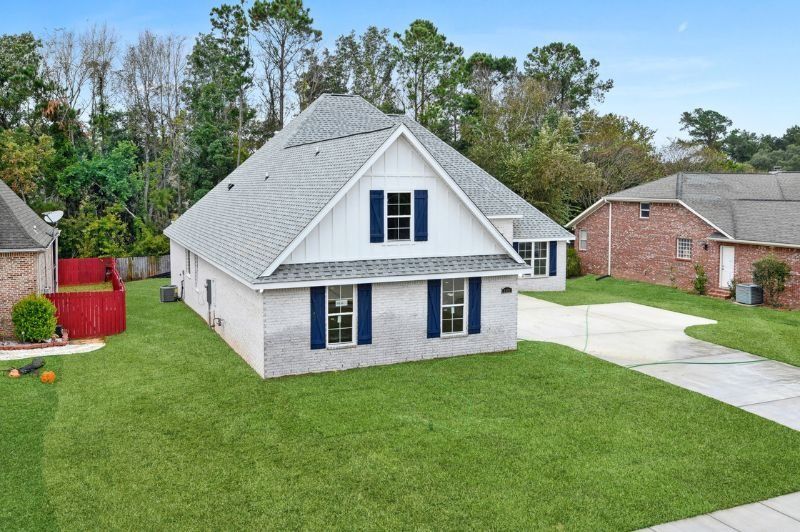 Light brick house with white trim, blue shutters, gray roof, and green lawn.