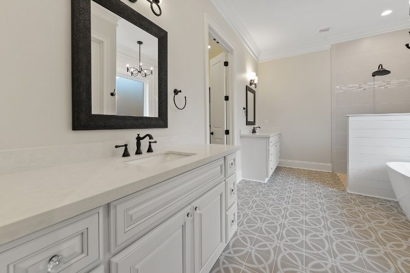 Elegant white bathroom with patterned tile floor, white cabinets, and black fixtures.