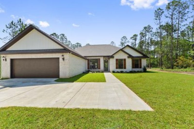 A modern, one-story house with a brown garage door and brick siding, situated on a grassy lawn.