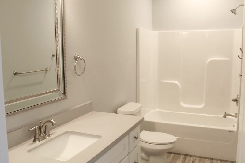 Bathroom with white walls, vanity, toilet, tub, and shower.
