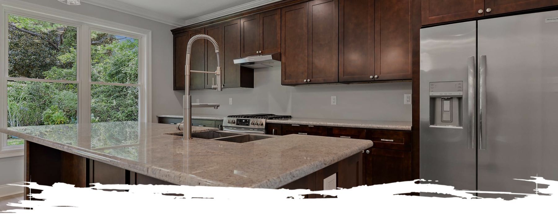 Kitchen with dark brown cabinets, stainless steel fridge, and granite countertops.