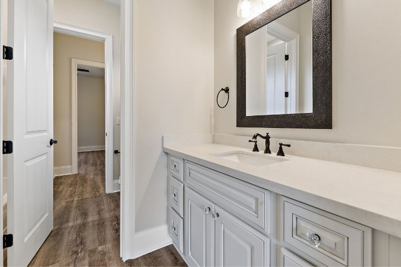 White bathroom with vanity, mirror, and hallway. Black fixtures and hardware.