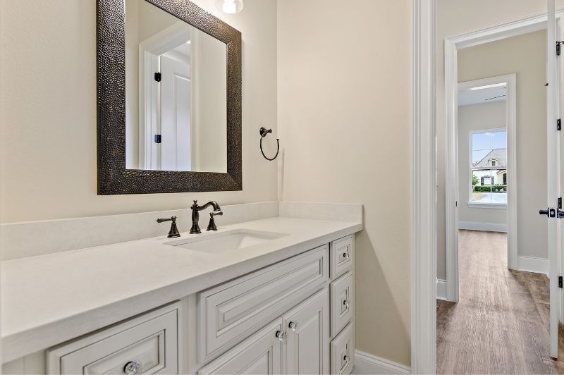 Bathroom with white vanity, black faucet, mirror, and open doorway to a hallway.