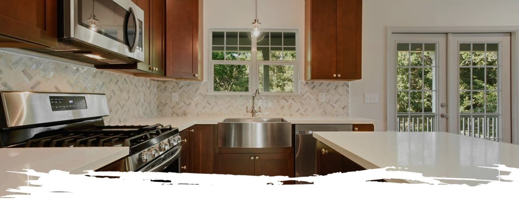 Kitchen with stainless steel appliances, brown cabinets, and white countertops. French doors and a window are visible.