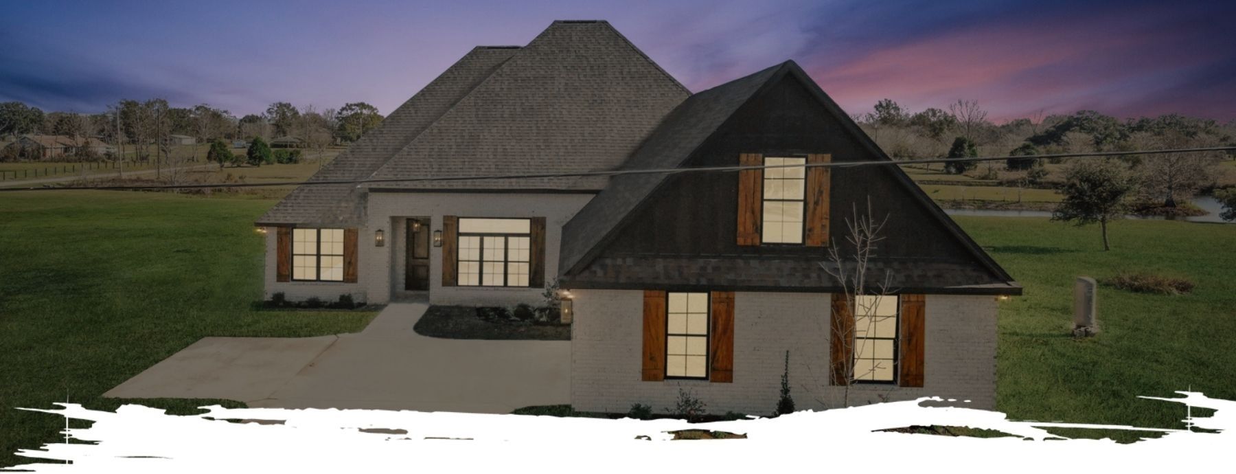 A large house with a gray roof and white walls. The sky is dusk with the green grass in the front.