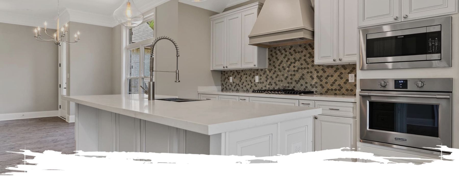 White kitchen with an island, stainless steel appliances, and tile backsplash.