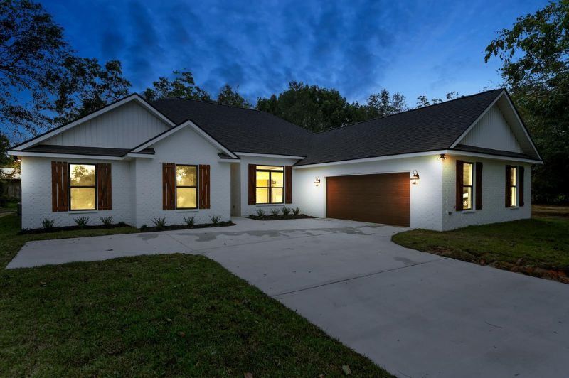 White house with brown shutters, garage, and driveway against a twilight sky.