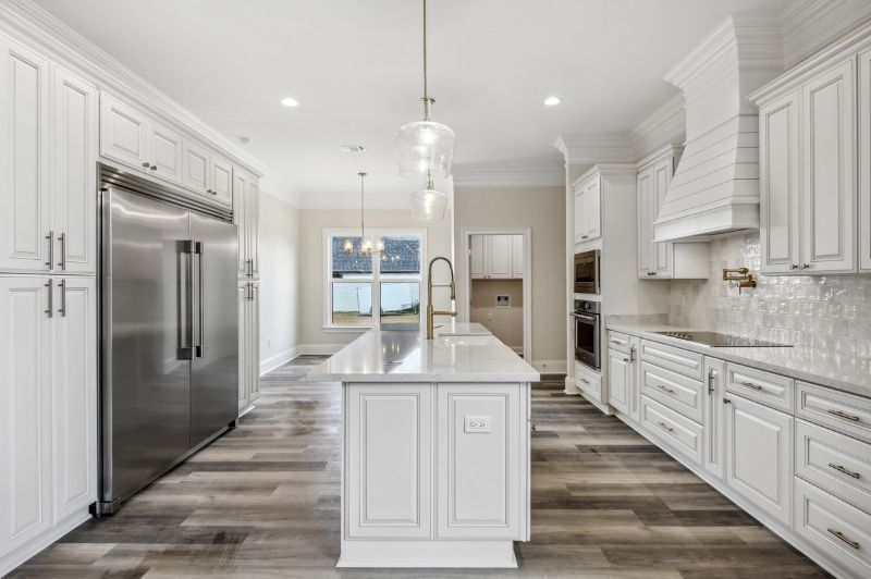 White kitchen with island, stainless steel appliances, and gray wood-look flooring.