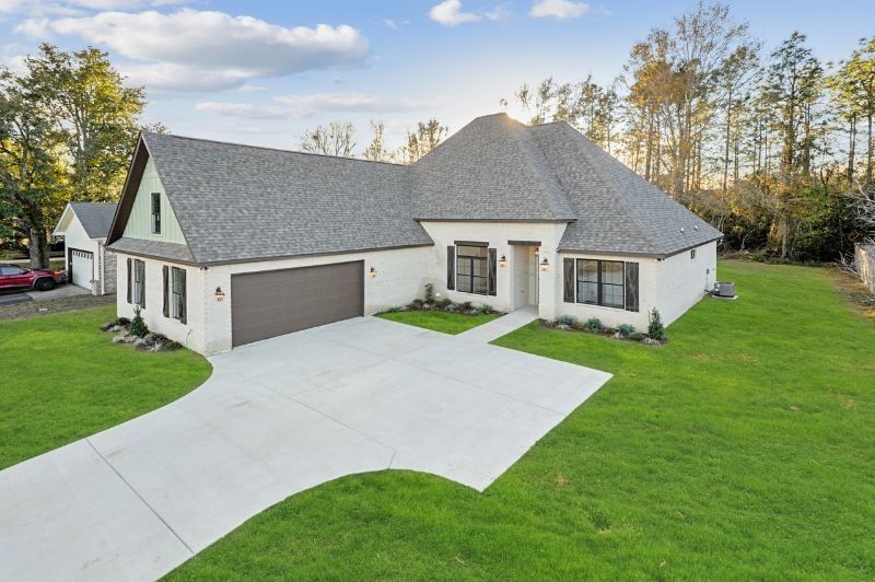 A modern, white brick house with a gray roof, brown garage door, and green lawn.