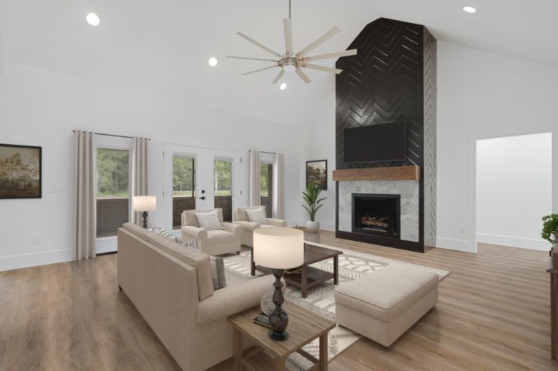 Spacious living room with fireplace and a high ceiling, featuring neutral tones and natural light.