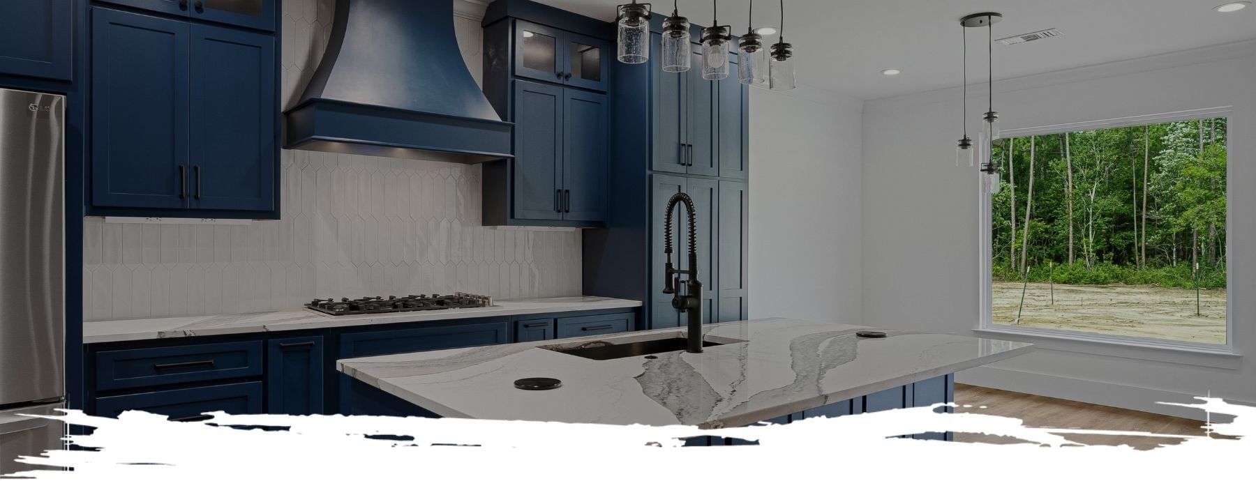 Modern kitchen with navy blue cabinets, white countertops, and a window overlooking trees.