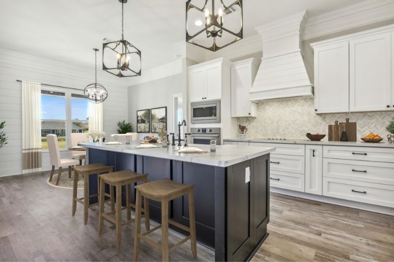 Modern kitchen with dark blue island, white cabinets, and wooden stools.