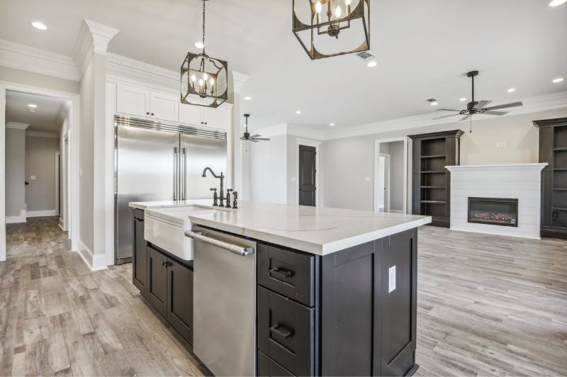 Modern kitchen with island, stainless steel appliances, dark cabinets, and light wood floors.