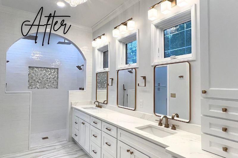 White bathroom with arched shower, marble countertops, three vanity mirrors, gold accents.
