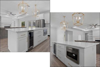 Modern kitchen with white cabinets, island with appliances, gold light fixtures.