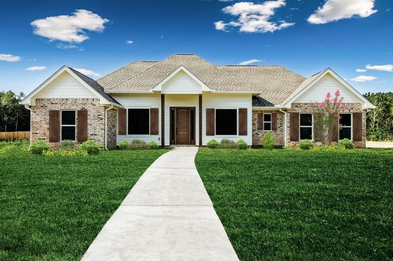 Ranch-style house with brown shutters, brick accents, and a concrete walkway under a blue sky.