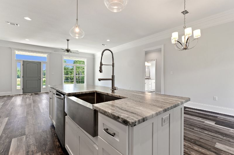 Kitchen island with stainless steel sink, granite countertop, and white cabinetry.