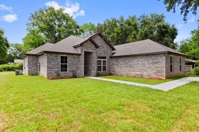 Brick house with green lawn and trees.