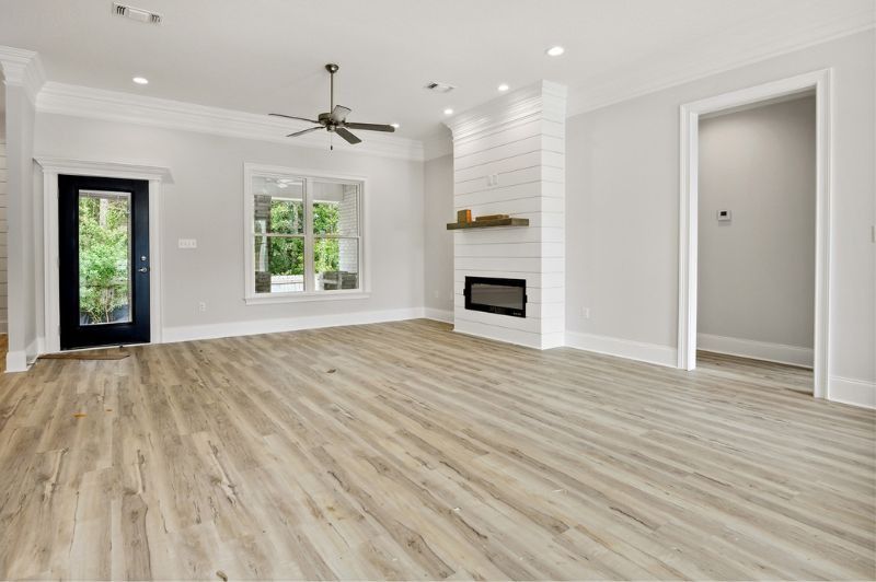 Empty living room with wood floors, fireplace, and natural light.