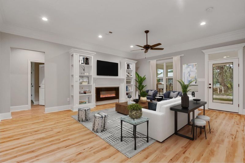 Spacious living room with hardwood floors, fireplace, white sofa, and windows.