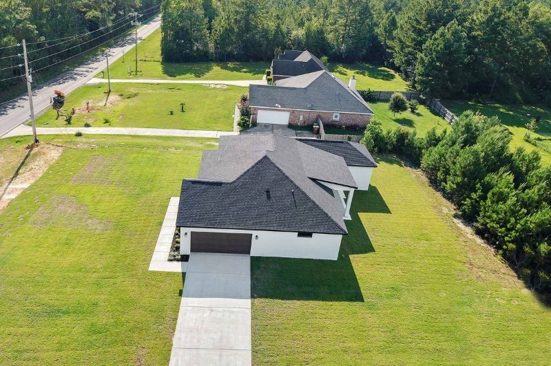 Aerial view of several houses with black roofs and green lawns.