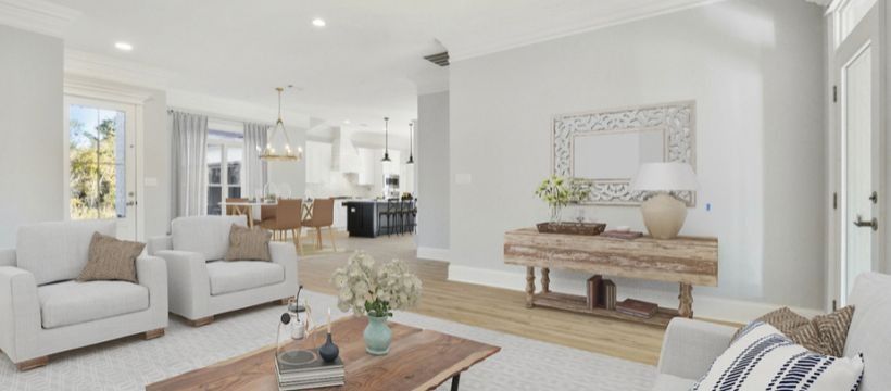 Bright, airy living room with white furniture, light wood floors, and an open view of the kitchen.