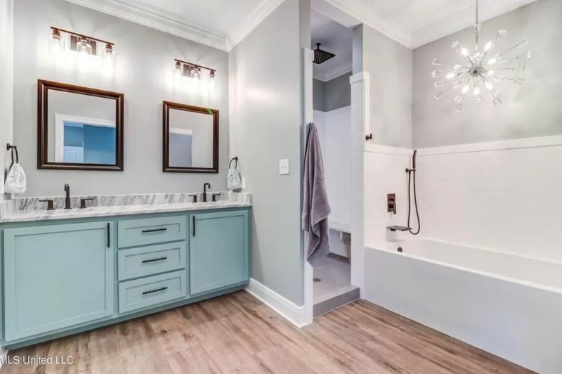 Modern bathroom with teal vanity, two mirrors, a shower, and bathtub.
