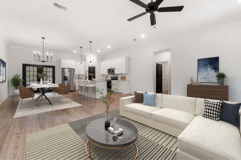 Open-concept living space with a white sectional, dining area, and kitchen; hardwood floors, neutral colors.