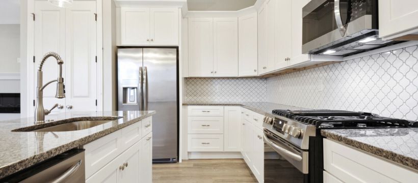 Bright, white kitchen with stainless steel appliances, granite countertops, and white cabinets.