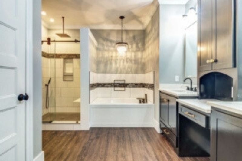 Bathroom with shower, built-in bench, dark cabinets, and wooden floor. Soft lighting and neutral colors.