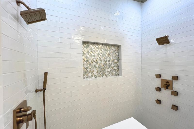 Modern white tile shower with bronze fixtures and built-in niche.