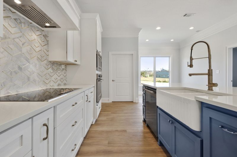 Modern kitchen with white cabinets, blue island, and stainless steel appliances.