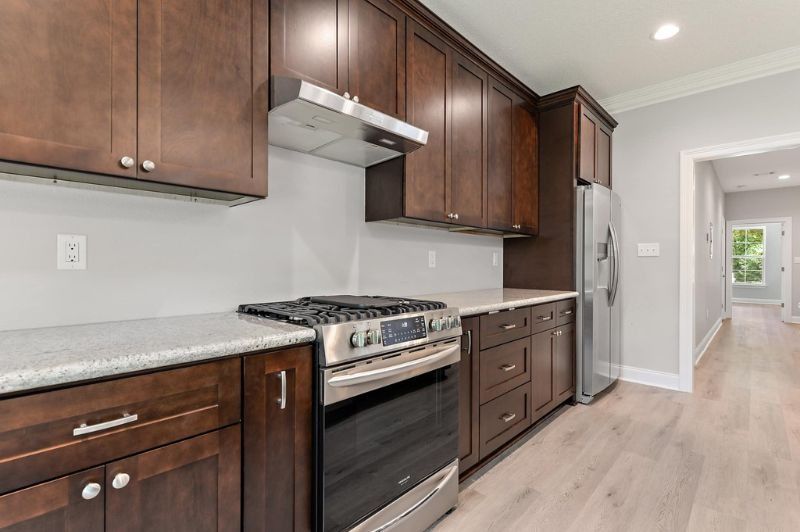 Kitchen with dark wood cabinets, stainless steel appliances, light countertops, and gray walls.