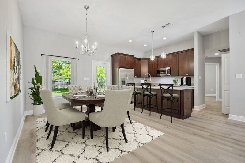 Dining area with dark cabinets, table, chairs, and rug; kitchen with bar and stools.