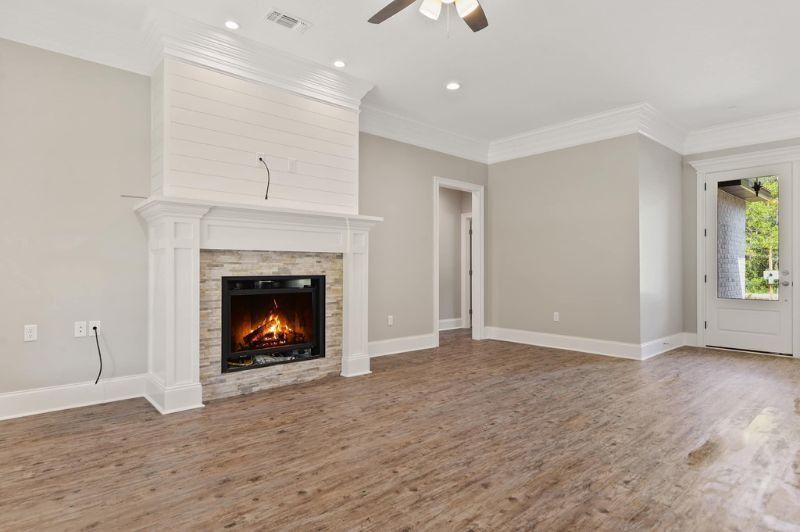 Living room with fireplace, wood floors, gray walls, and white trim.