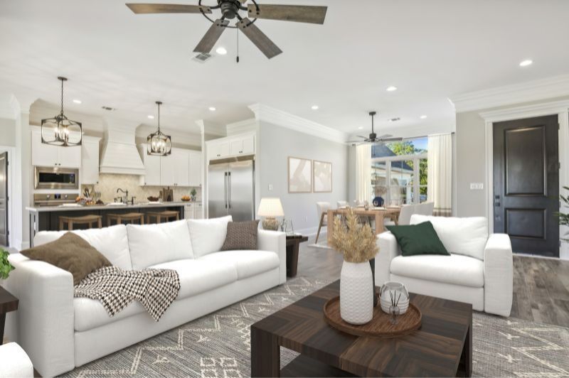 Spacious open-concept living area with white couches, dark wood table, and kitchen in the background.