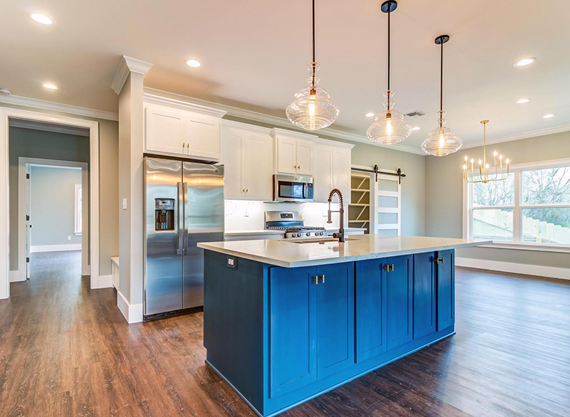 Kitchen with blue island, white cabinets, and stainless steel appliances.